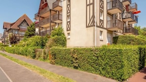A modern multi-story building with balconies and a well-maintained hedge along the street. - Le Clos Mathilde by Interhome (Cabourg)
