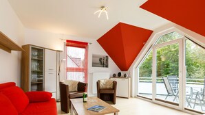 A modern living room with a red sofa, a wooden coffee table, and a dining area with chairs. - Apartment Preiss by Interhome (Zinnowitz)