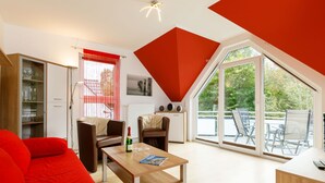 A modern living room with a red couch, a wooden coffee table, and a dining area with chairs. - Apartment Preiss by Interhome (Zinnowitz)
