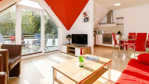 A modern apartment with a dining area, kitchen, and a large glass door leading to a balcony. - Apartment Preiss by Interhome (Zinnowitz)