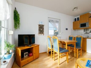 Un ambiente compatto con zona pranzo, cucina e televisore.