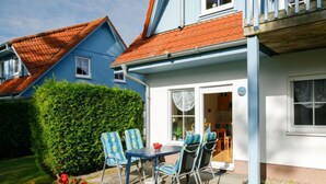 A house with a blue exterior, a red roof, and a small patio with a table and chairs. - Apartment Berg by Interhome (Zinnowitz)