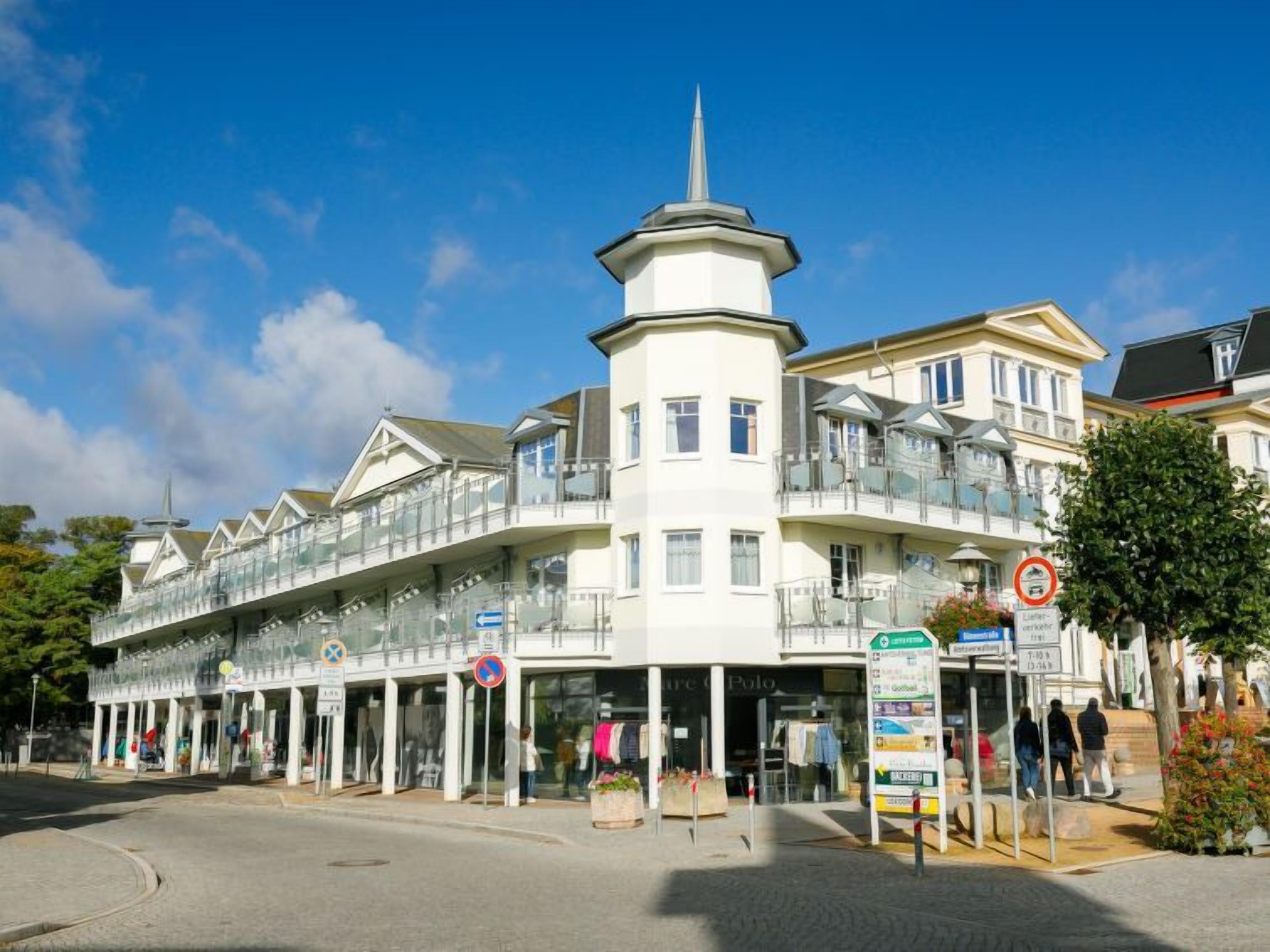 A multi-story hotel with a prominent tower, balconies, and a covered walkway.