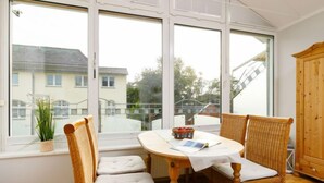 A room with a large window, wicker chairs, a table with a white tablecloth, and a wooden cabinet. - Luise von Preußen (App. 205) by Interhome (Zinnowitz)