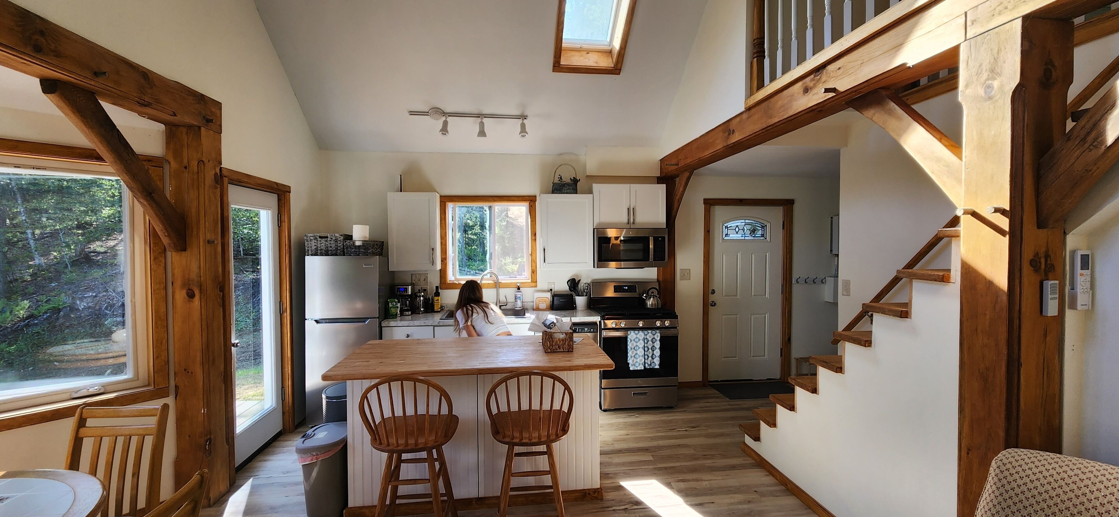 A kitchen with wooden beams, a central island with two bar stools, a microwave, and a stove.