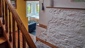 Eine Treppe mit hölzernen Geländern, einer weißen, strukturierten Wand und einem Fenster mit Blick ins Freie.