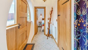 A hallway with wooden doors, a hanging light fixture, and a patterned curtain.