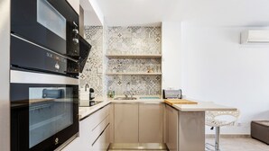 A compact kitchen with a built-in oven, a sink, and a small bar area with a stool. - WELCS APARTAMENTO 078 EMP  con inmejorables vista (Empuriabrava)