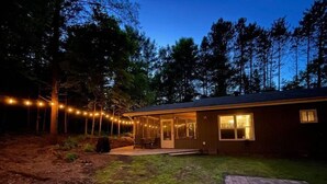 A single-story house with a covered patio and string lights. - The Muskoka Room Huntsville with Hot Tub (Huntsville)