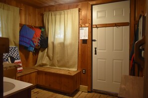 A wooden cabin bathroom with a bench, a white door, and a shower curtain.