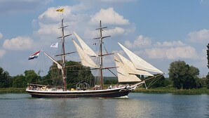 Un barco de vela alto con varios mástiles y velas, navegando sobre el agua.
