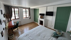 Un dormitorio con cama, escritorio, silla, chimenea y televisor.