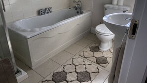 Een badkamer met een bad, toilet en wastafel.
