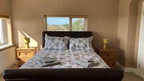 Een slaapkamer met een bed, twee nachtkastjes, een raam en een radiator.
