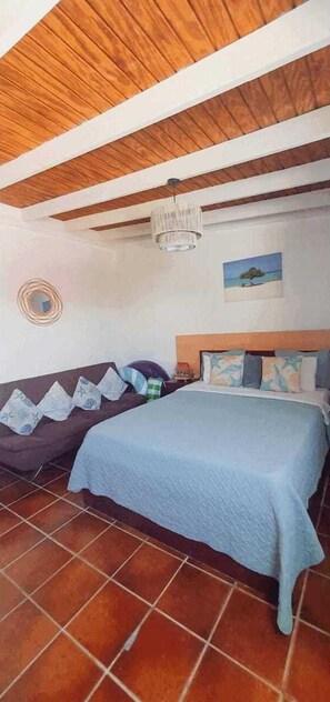 Cozy retreat with a comfortable bed, sofa, and mirror.