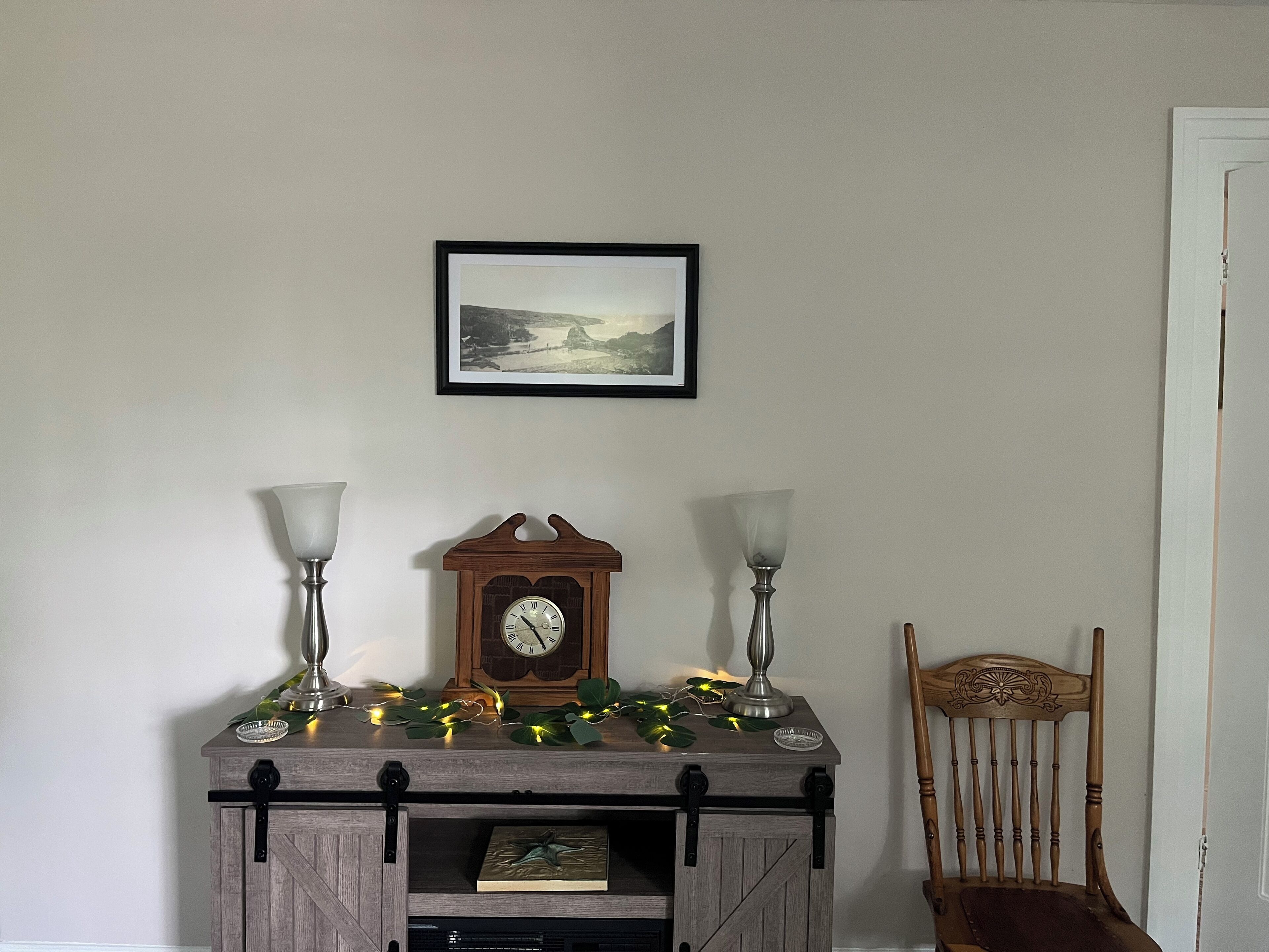 A room with a wooden cabinet, a clock, and a chair.
