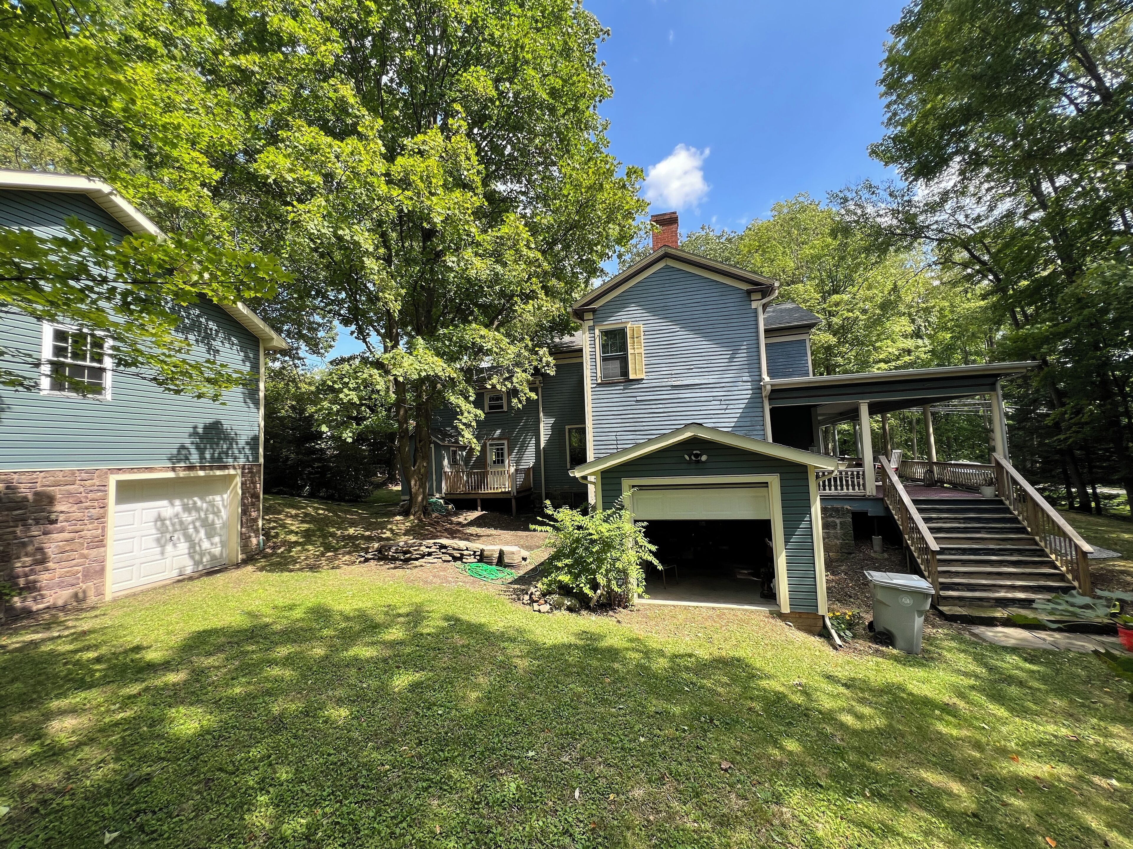 A two-story house with a garage, a covered porch, and a stone foundation.