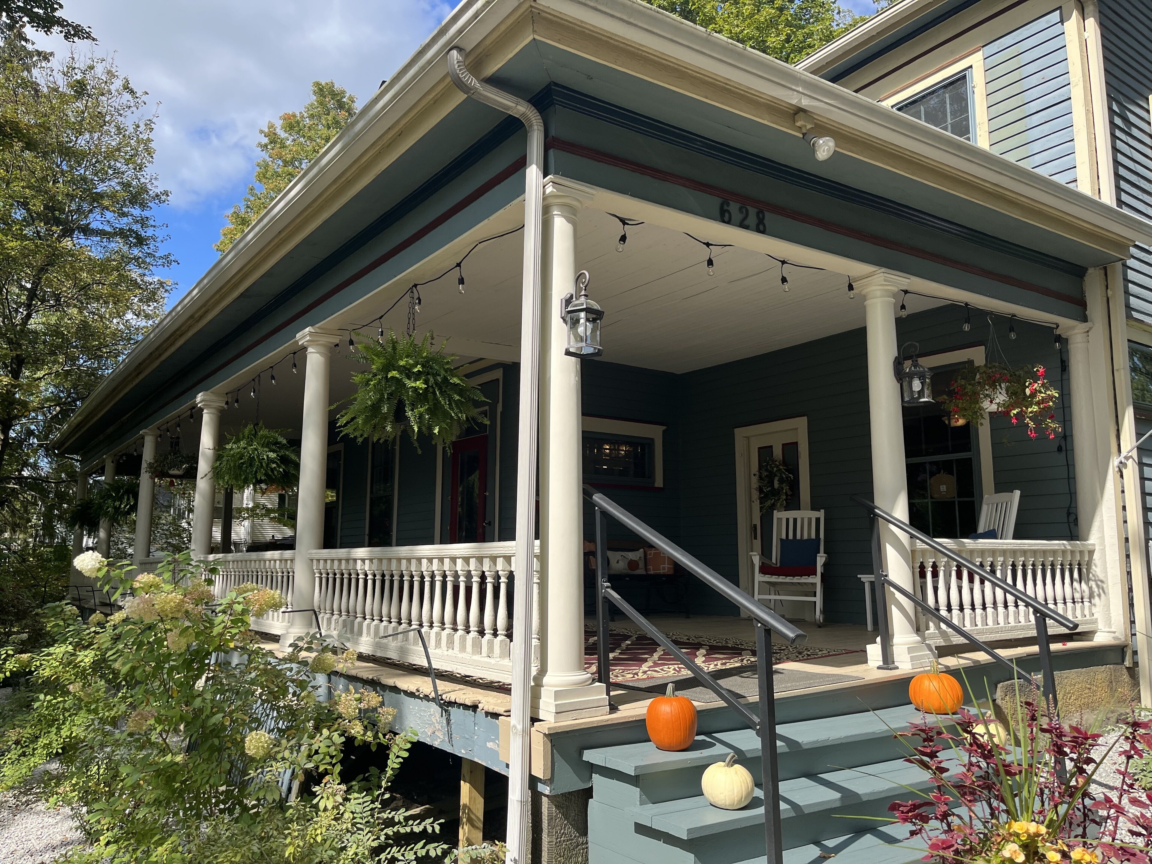A two-story house with a porch, columns, and a staircase leading to the second floor.