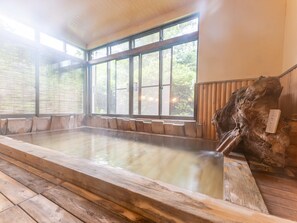 Un baño de aguas termales con bancos de madera y una escultura de madera.