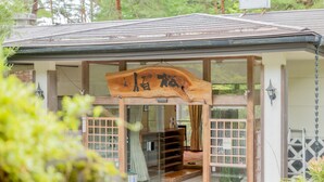 Un edificio japonés tradicional con un letrero de madera, puertas de cristal y un banco de madera afuera.