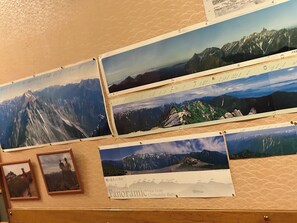 A wall with multiple panoramic photographs of mountain landscapes. - hinokiyunoyado syouhaku (Azumino)