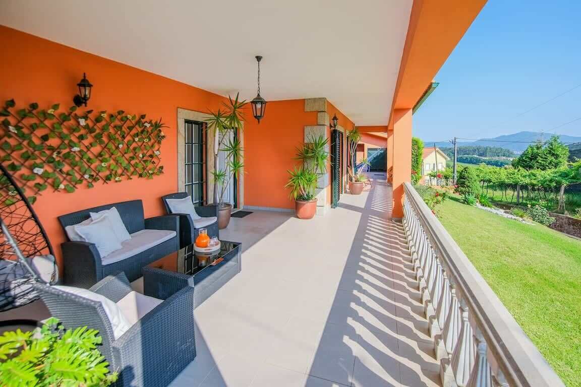 A balcony with outdoor furniture, potted plants, and a view of a vineyard.