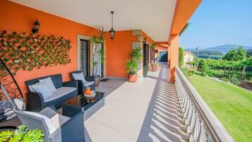 A balcony with outdoor furniture, potted plants, and a view of a vineyard.
