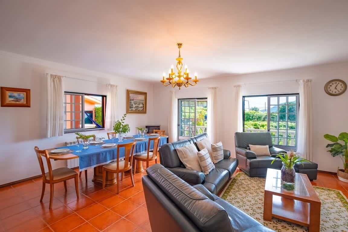 A living room with a sofa, dining table, chairs, and a chandelier.