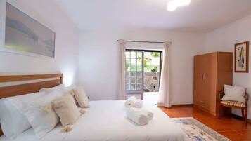 A bedroom with a bed, a wardrobe, a chair, and a view through a door.