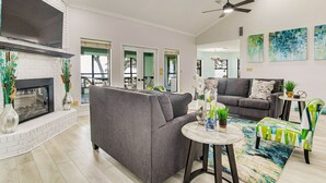 A modern living room with a fireplace, grey sofas, a round coffee table, and a ceiling fan.
