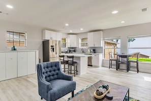A modern kitchen with white cabinets, a central island, and a dining area with a table and chairs.