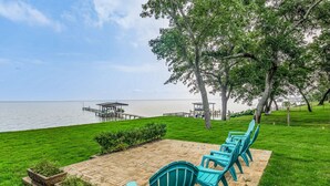 A patio with chairs and a view of the lake. - Gulf Breeze Bayfront Bungalow - Dock - Pet-Friendly - Near Pensacola Beach (Gulf Breeze)