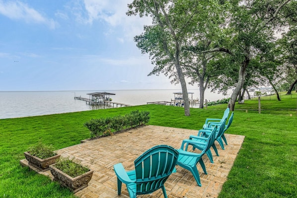 A waterfront patio with chairs and a small garden area.