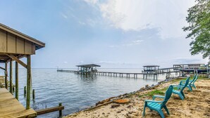Een pier aan het strand met houten looppaden en blauwe stoelen.