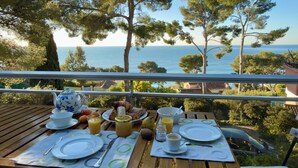 Ett dukat bord för frukost med utsikt över havet och träden.