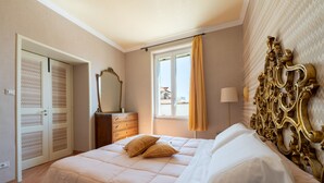 A bedroom with a bed, a dresser, a mirror, and a window with curtains.