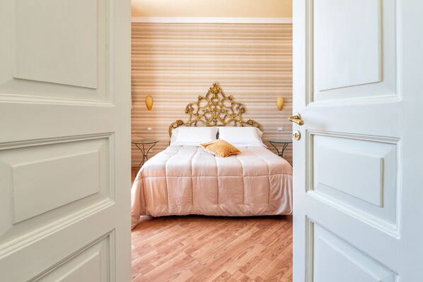 A bedroom with a bed, a wooden floor, and a patterned wall. - Amalpha Domus Apartment (Amalfi)