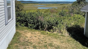 A house with a view of a lake and grassy area. - Cozy two bedroom home with ocean view. Quiet and secluded location.  (Lubec)