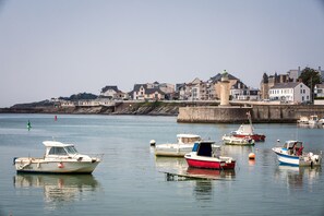 A harbor with boats docked, a stone wall, and buildings along the coastline.