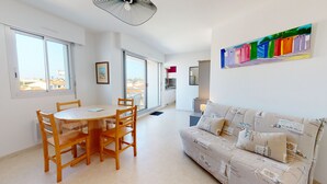 A modern apartment with a dining area, a sofa, and a kitchen.