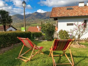 A house with a tiled roof, a lamp post, and a grassy lawn with two wooden chairs. - Basaburu - Sare - Gîte (SARE)
