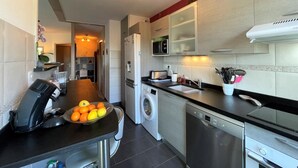 Una cocina moderna con encimera negra, electrodomésticos de acero inoxidable y horno empotrado.