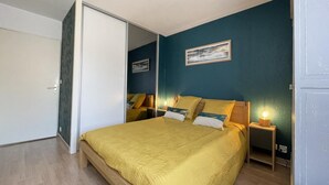 Un dormitorio con cama, mesitas de noche, un cabecero y una pared decorada con un cuadro.