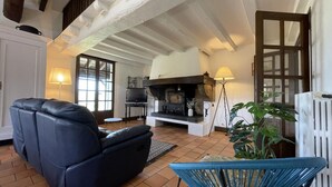 A cozy living room with a fireplace, a sofa, a chair, and a TV.