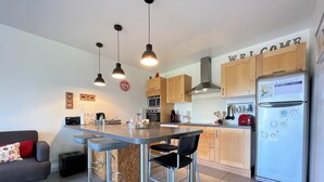 Una cocina moderna con una isla central, taburetes de bar, un refrigerador y armarios de madera.