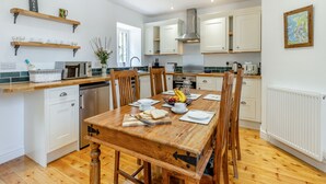 Une cuisine moderne avec des meubles blancs, une table à manger en bois et divers appareils de cuisine.