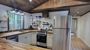 Una cocina moderna con suelo de madera, un refrigerador de acero inoxidable y un horno empotrado.