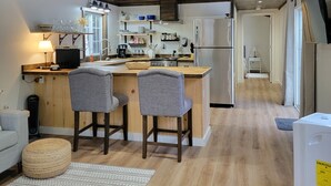 Una cocina moderna con vigas de madera en el techo, una isla central con taburetes de bar y un refrigerador.