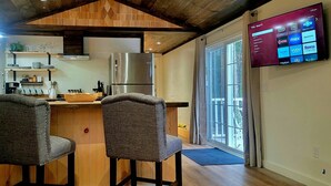 Cocina moderna con detalles de madera, un refrigerador grande y un televisor de pantalla plana montado en la pared.