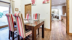 Un coin repas avec des chaises à rayures, une table en bois et une vue sur l’extérieur.